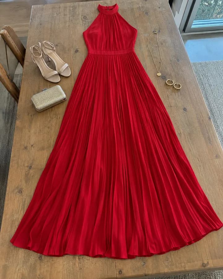 Flat lay garment photo: a red pleated halter maxi dress laid flat on a wooden table